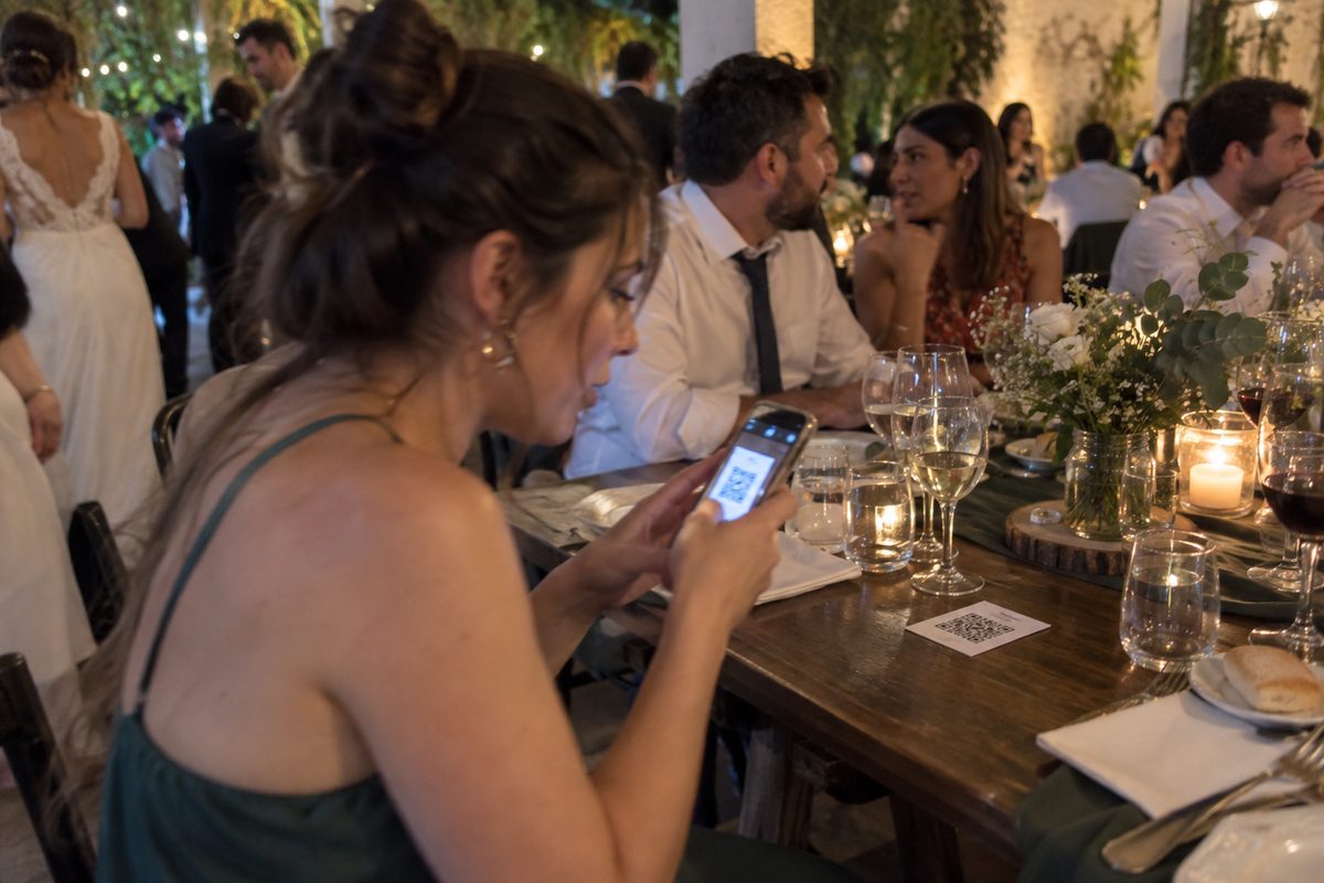 Una invitada escanea con el celular el código que está sobre la mesa del casamiento
