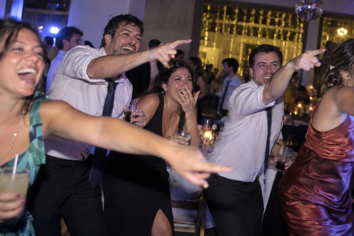 Un grupo de invitados festeja y señala la pantalla desde la pista de baile